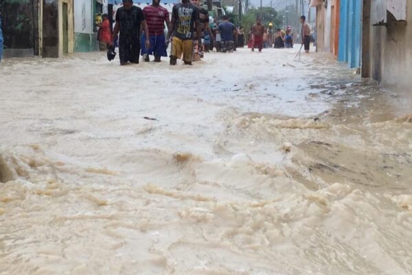 People walking through flooded street during heavy rain.