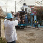 Man in blue hat waves at passing truck.