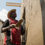 Man plastering wall under sunny sky.