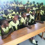 Children in uniforms sitting attentively in classroom.