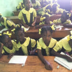 Children in classroom wearing yellow uniforms.