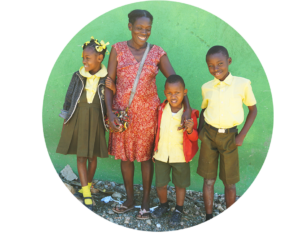 Smiling woman and three children in front of green wall.