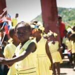 Children in yellow holding flags during a parade.