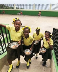 Children in uniforms with meals on school steps