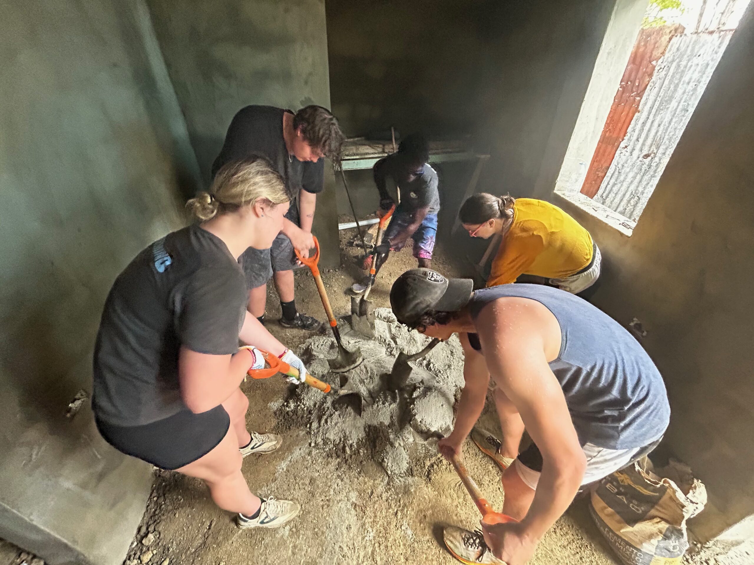 Group mixing concrete inside a building under construction.