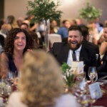 People enjoying dinner event, smiling and talking.