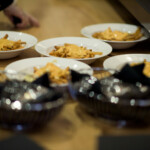 Plates of cheese fries on wooden table.