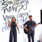 Musicians performing in front of artistic backdrop.