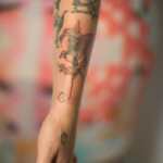 Forearm tattoos featuring flowers and a bird design.
