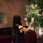Person hanging notes on a decorated tree indoors.