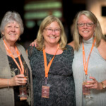 Three women smiling at an event.