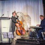 Musicians performing with double bass and keyboard on stage.