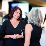 Women talking at a formal event.