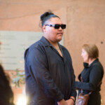 People attending an event, wearing sunglasses indoors.